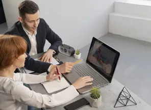 Two professionals reviewing an analytics dashboard on a laptop